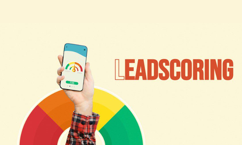 En hånd holder en smartphone, der viser en app med en farverig lead scoring skala og ordet "LEADSCORING" i orange til højre