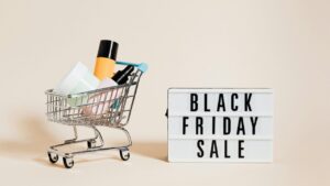 En lille indkøbsvogn fyldt med skønhedsprodukter ved siden af en lysboks med teksten 'Black Friday Sale