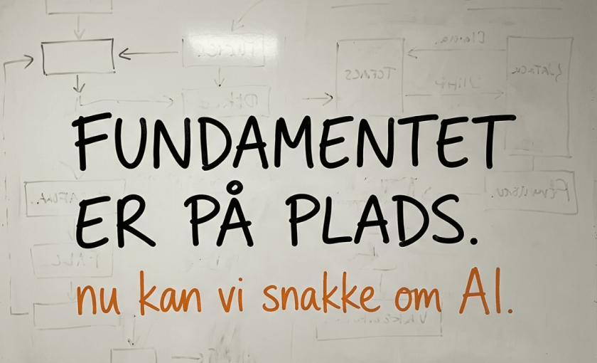 Whiteboard med udviskede automation-flows i baggrunden og teksten Fundamentet er på plads, nu kan vi snakke om AI